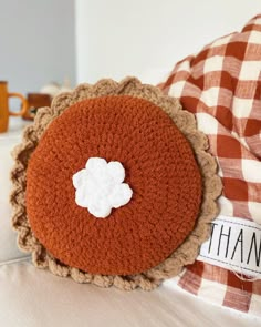 a close up of a crocheted pillow on a bed with a name tag