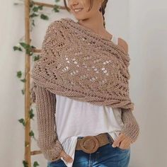 a woman wearing a knitted shawl and jeans