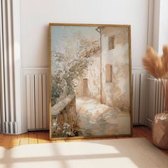 a painting is on the floor next to a vase with some dry grass in it