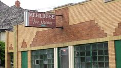 a brick building with green shutters and a sign that says melchose ice cream