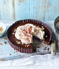 a chocolate pie with whipped cream and nuts on top