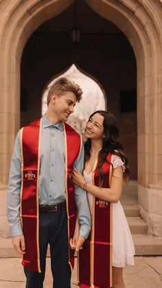 a man and woman standing next to each other in front of a building with arches