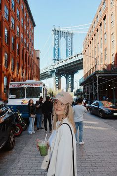 a woman is standing on the street with a drink in her hand