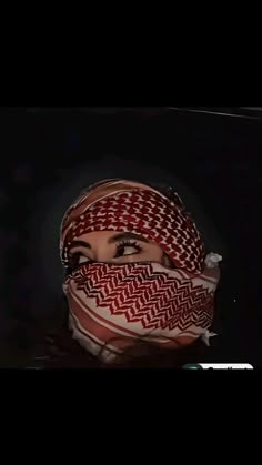 a woman wearing a red and white patterned head scarf with her eyes closed in the dark