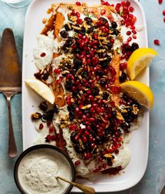 a white plate topped with fish covered in pomegranates and garnish