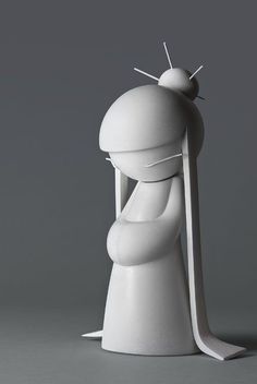 a white sculpture sitting on top of a gray floor next to a tall object with two pins in it's head