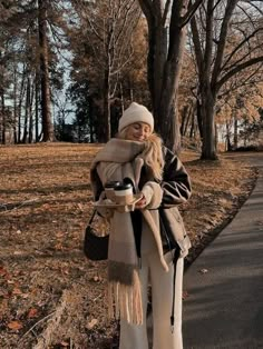 a woman standing next to a tree holding a coffee cup