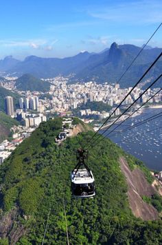 a cable car going up the side of a mountain with a city in the background