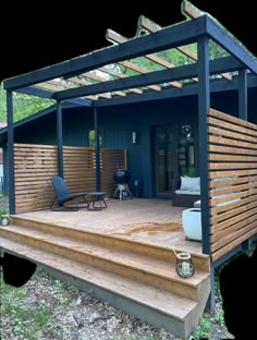 a wooden deck with chairs on it and a pergolated area in the background