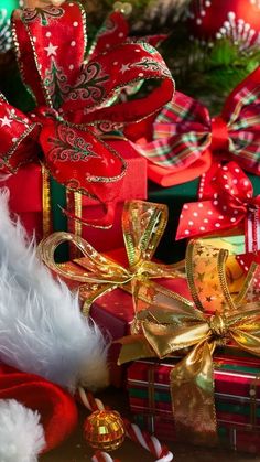 many presents are wrapped in red and gold ribbons with bows on them, along with other christmas decorations