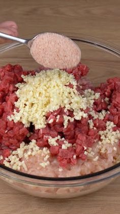 a bowl filled with ground beef and other ingredients to make meatloaf on a wooden table