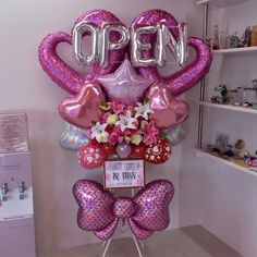 an open sign with balloons and flowers in the shape of flamingos on display at a store