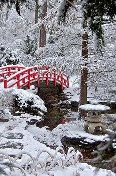 a red bridge over a small stream in the snow