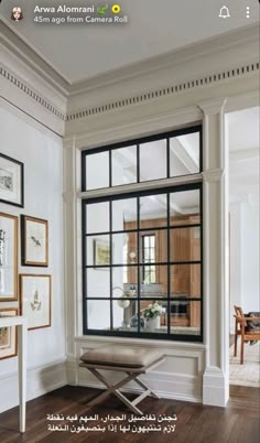 an open window in a white room with wood floors and framed pictures on the wall