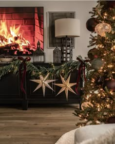 a decorated christmas tree in front of a fire place with two star decorations on it