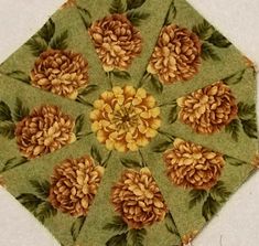 an image of a green and yellow quilt with pine cones on it's center