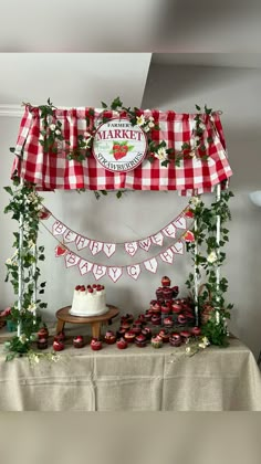 a table topped with lots of cupcakes under a red and white checkered canopy