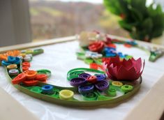 a close up of a flower on a table with buttons and other crafting supplies