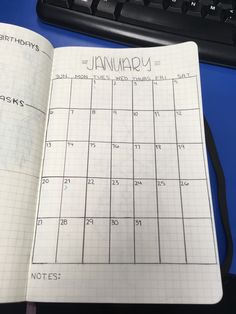 an open calendar book sitting on top of a desk next to a keyboard