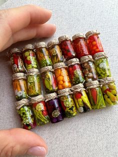 a hand holding a jar filled with lots of different types of vegetables