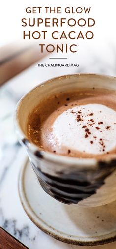 a cup of hot chocolate on top of a saucer with the words get the glow superfood hot cacao tonic