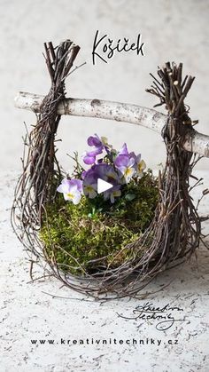 a small bird nest with purple flowers in it