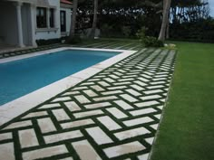 an outdoor swimming pool with grass on the ground next to it and trees in the background