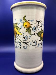 a white vase with blue and yellow designs on it's sides, against a blue background