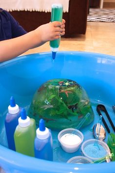 a child is playing in a blue tub filled with water and other items to make an ocean animal rescue