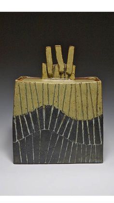 a small ceramic container with sticks sticking out of it's sides, on a gray background