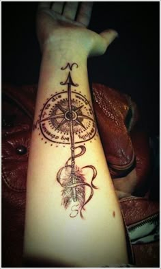 a woman's arm with a compass tattoo on it