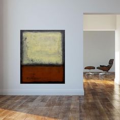 an abstract painting hangs in the corner of a white room with wooden floors and chairs