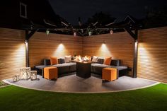 an outdoor seating area lit up at night with string lights on the wall and lawn