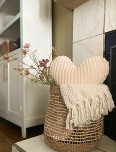 a basket with flowers in it sitting on top of a table next to a fireplace