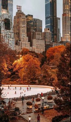 people skating on an ice rink surrounded by tall buildings