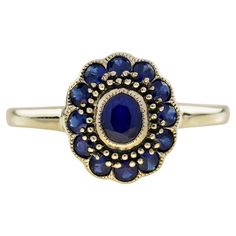 A vintage style dress ring containing an approx. 0.43 carat oval blue sapphire center stone, accented with a timeless halo of twelve blue sapphires petals. Finely crafted in yellow gold, this lovely ring features intricately detailed milgraning edged. Ring Information Style: Vintage Metal: 9K Yellow Gold Weight: 1.98 g. (approx. total weight) Ring size: US 7 (resizable) Center Gemstones Type: Blue Sapphire Shape: Oval Size: 5 x 4 mm. Number: 1 Weight: 0.43 Carat (approx. total weight) Accent Gem Floral Halo, Vintage Style Rings, Floral Ring, Blue Sapphire Diamond, Modern Ring, Vintage Style Dresses, Lovely Ring, Dress Rings, Natural Blue Sapphire