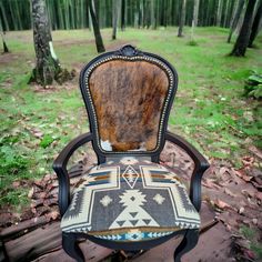 an old chair sitting on top of a wooden floor in the woods with trees and grass behind it