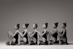 a group of women in leotards sitting on the floor with their backs turned