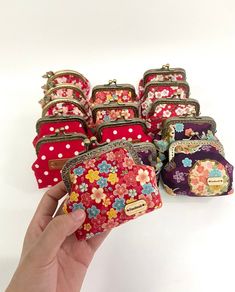 a hand holding a small purse next to several smaller bags with flowers on them and polka dots around the edges