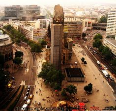 an aerial view of a clock tower in the middle of a busy city street with lots of traffic