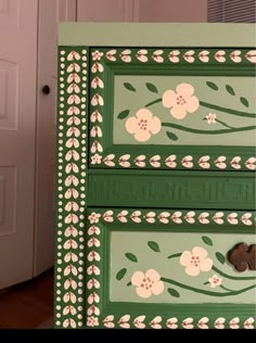 a green dresser with flowers painted on it