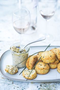 a white plate topped with scones next to a glass of wine