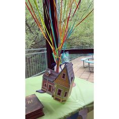 a house shaped vase sitting on top of a table next to a book and tree