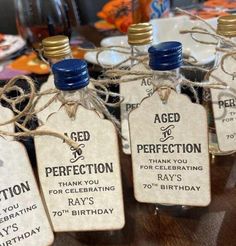 four bottles with labels on them sitting on a table next to plates and glasses in the background