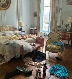 a bed room with a neatly made bed and lots of clothes on the floor