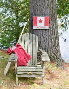 a wooden chair sitting next to a tree with a canadian flag on it's back