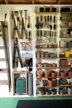 a room filled with lots of pots and gardening tools on shelves next to a ladder