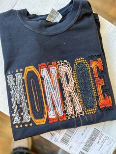 a t - shirt with the word monroe on it sitting on top of a newspaper