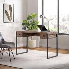 a desk with a laptop on it and a chair next to it in front of a window