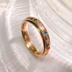 a gold ring with three different colored stones on the inside and outside, sitting on top of a white plate